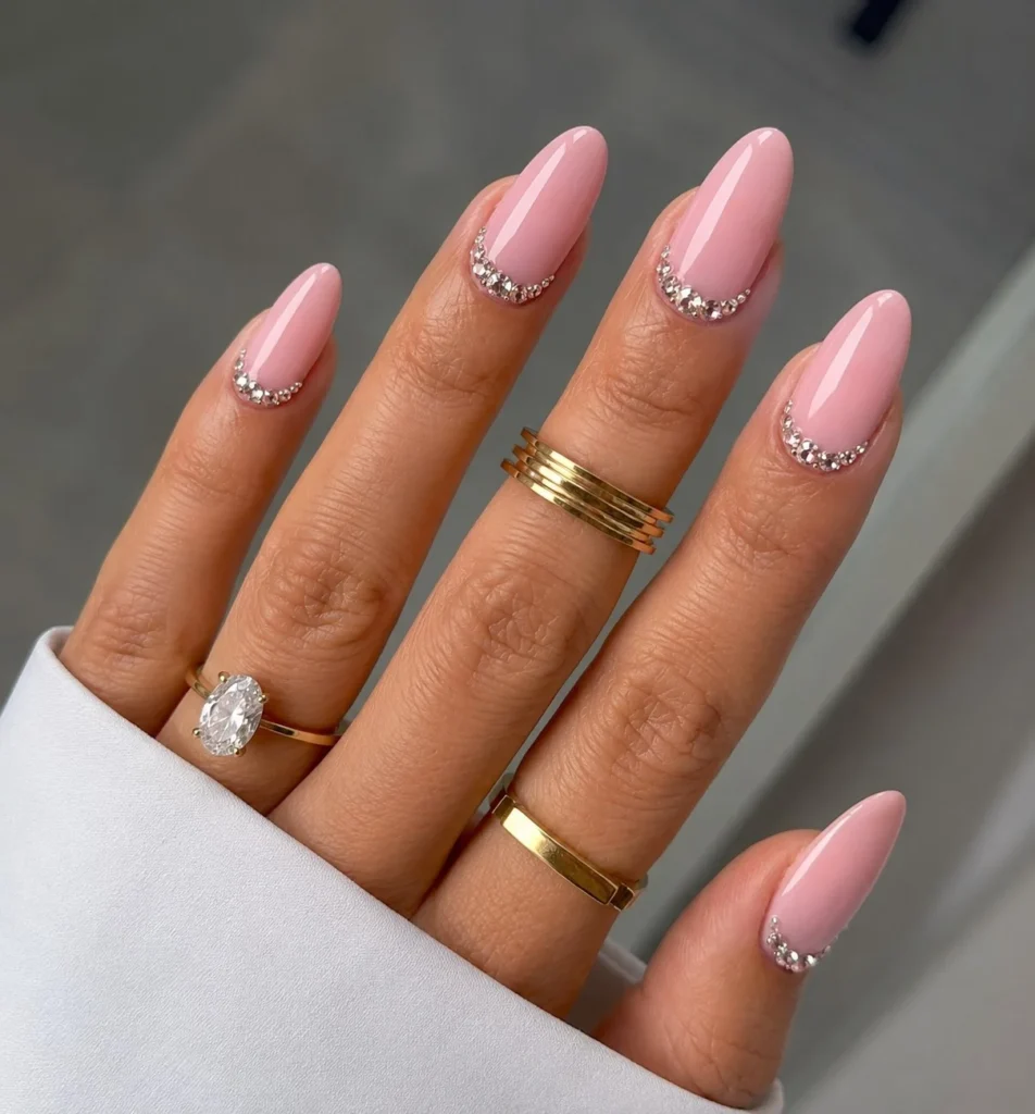 Pink nail designs featuring delicate rhinestone accents placed neatly along the cuticle line.