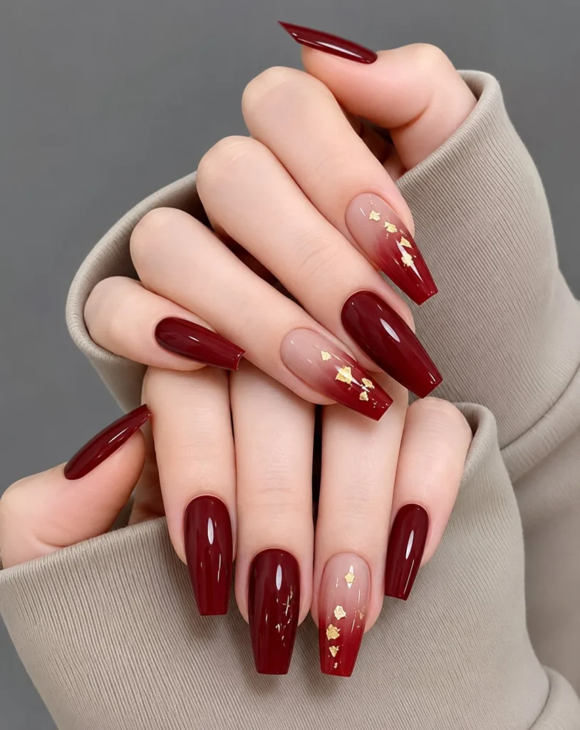 Bright ruby red coffin nail designs featuring elegant gold foil accents on glossy long nails.