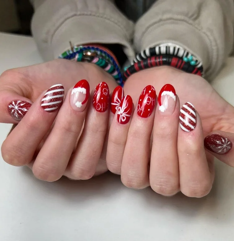 Cute Christmas nail designs featuring a tiny Santa hat accent on a glossy festive manicure.