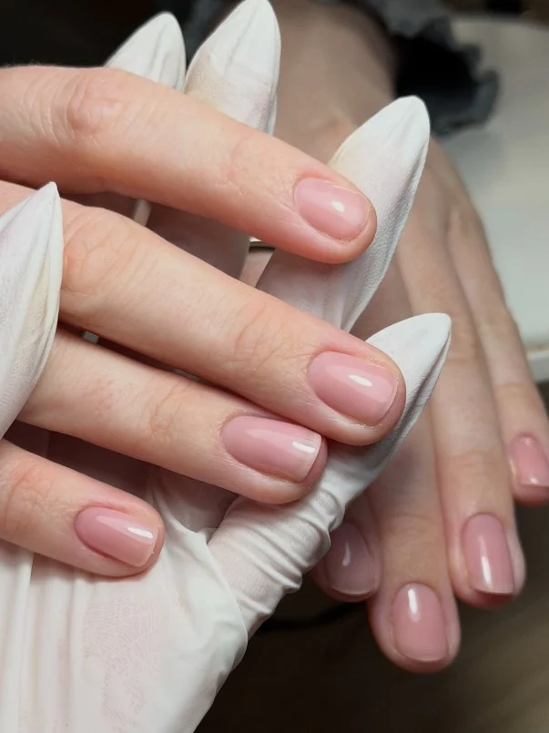 Sheer pink manicure completing a polished navy blue dress outfit.