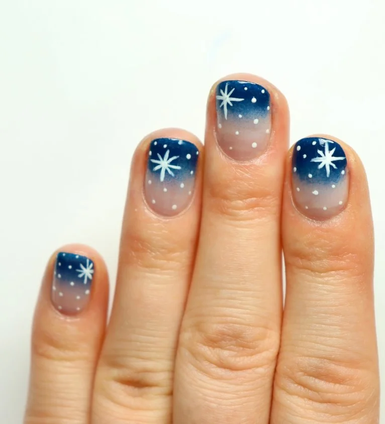 Cute Christmas nail designs with delicate white snowflakes over a sheer pink winter manicure.