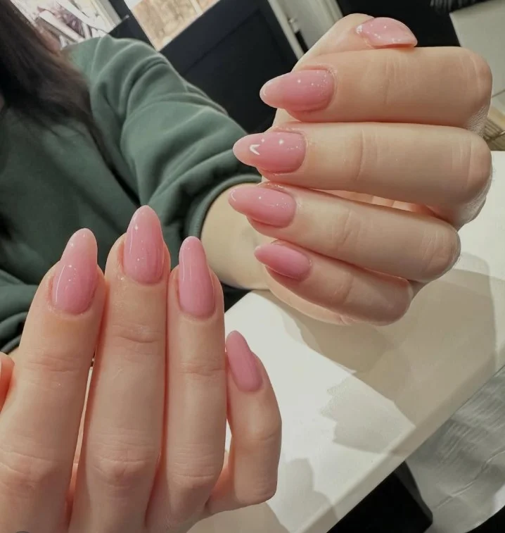 Soft pink manicure brightening a forest green dress with feminine style.