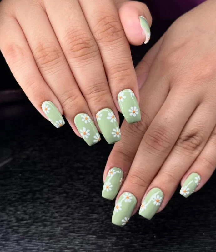 Square nail designs featuring tiny white daisy flowers on a soft pastel base with glossy finish.