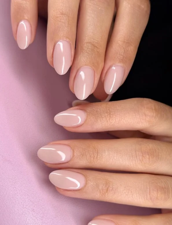 Warm nude nails complementing a navy blue dress with timeless style.
