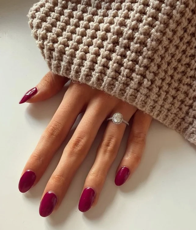 Berry nail polish complementing cool tan undertones with rich pink-red color.