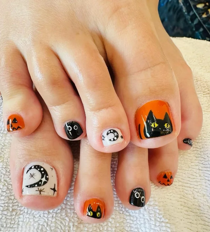 Black cat Halloween toe nail designs with tiny golden eyes on glossy black polish.