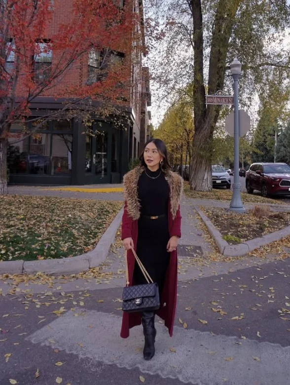 Woman wearing black knee-high boots with a simple black dress and a long coat.