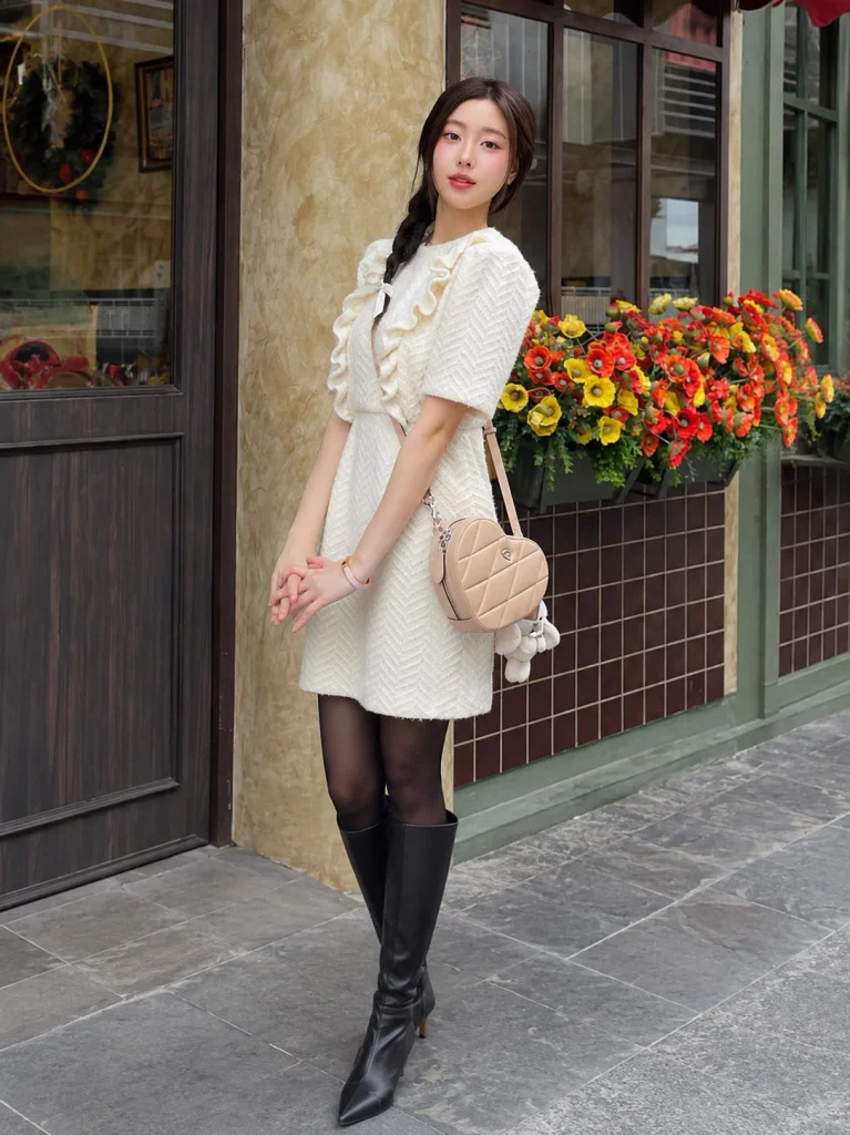 Woman wearing black knee-high boots with a knit mini dress and black tights.