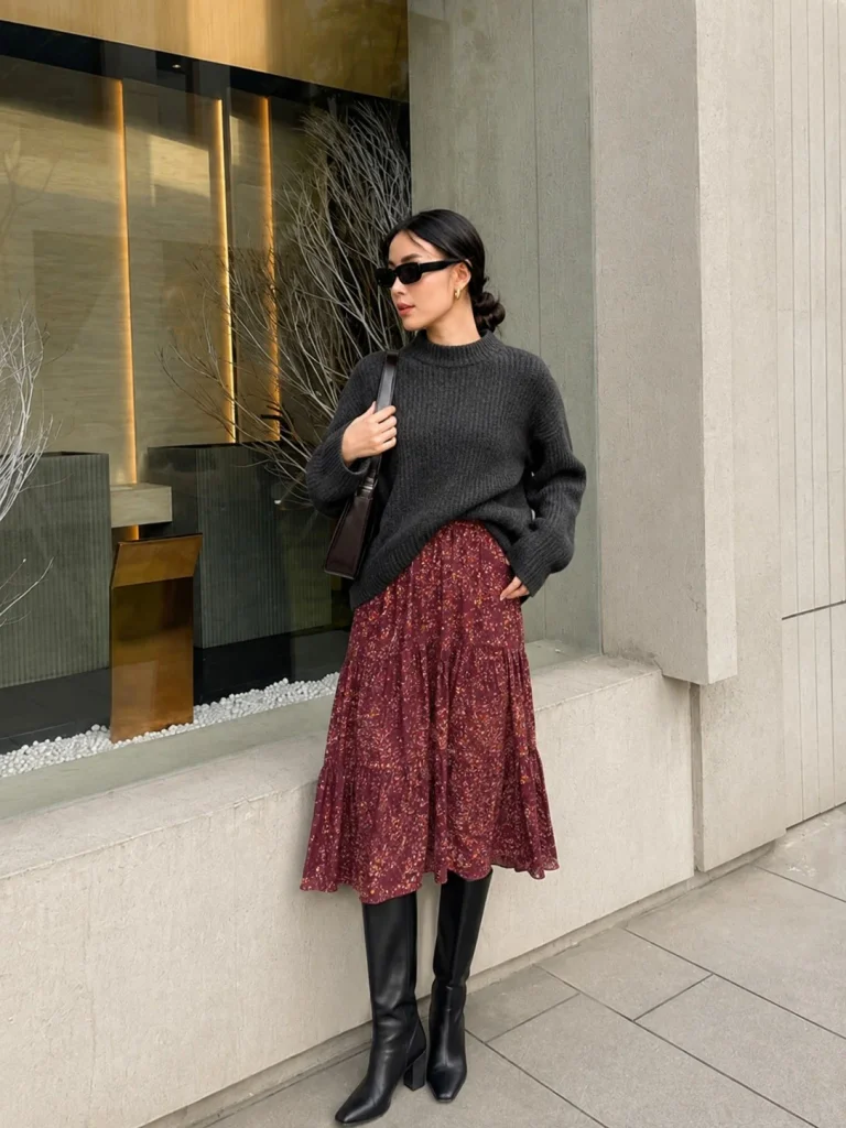 Woman wearing black knee-high boots with a midi dress and a chunky knit sweater.