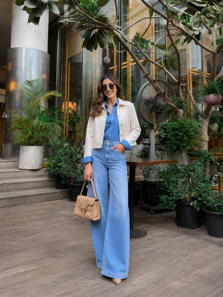 Woman wearing a blue denim shirt under a cropped jacket with wide-leg jeans.