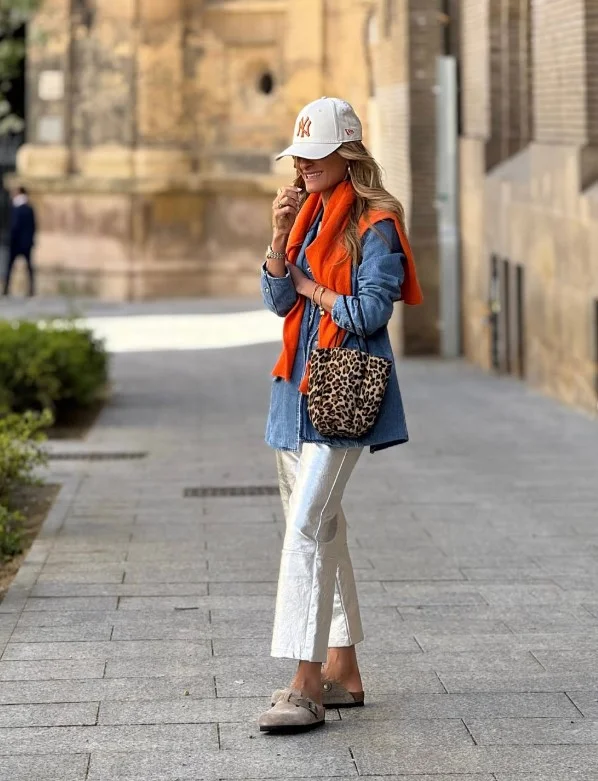 Woman wearing a blue denim shirt with silver metallic trousers.