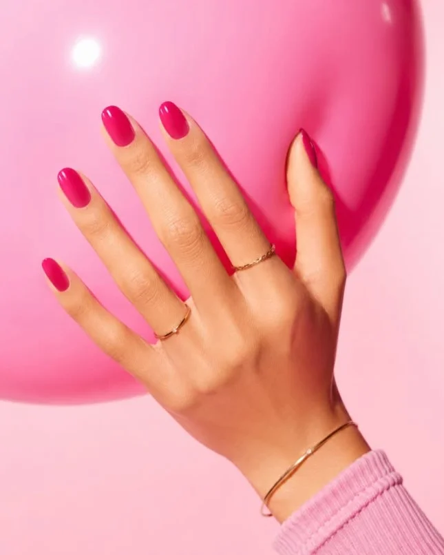 Bright fuchsia nail varnish creating a vivid playful manicure against pale skin.