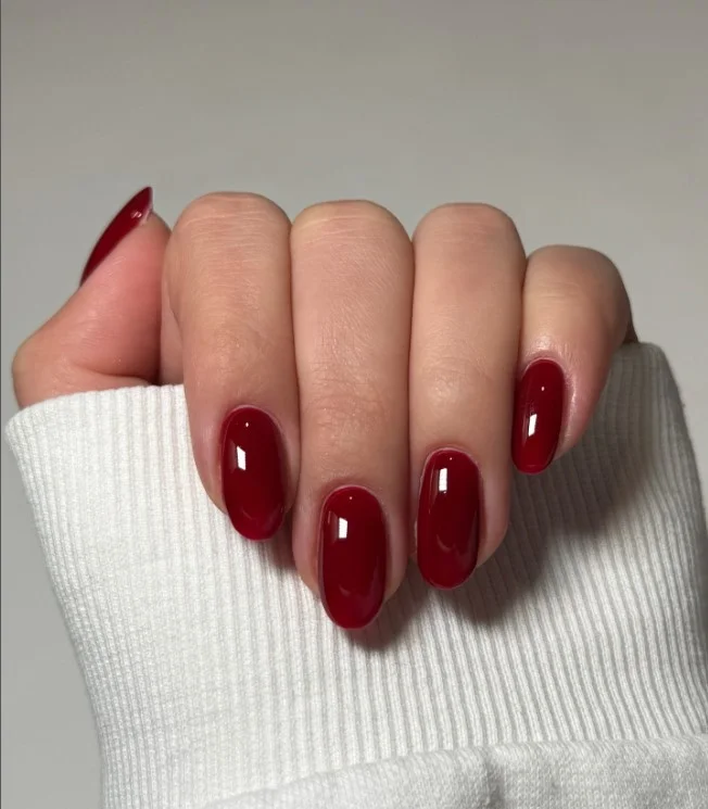 Bright cherry red nail varnish against pale skin for a bold polished manicure.