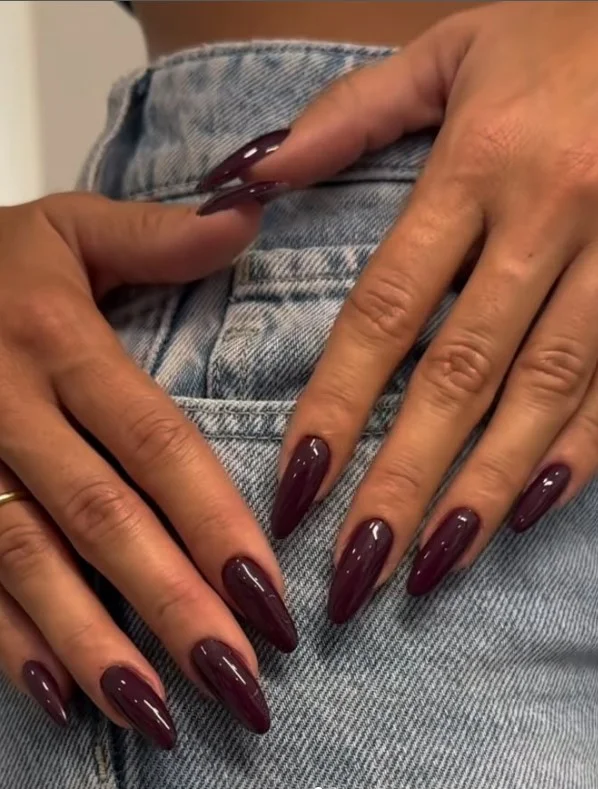 Deep burgundy nails giving tan skin a rich and sophisticated manicure look.