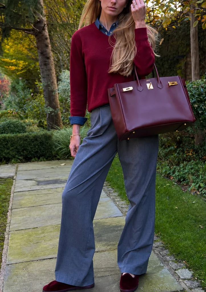 Woman wearing a blue denim button-up shirt under a burgundy sweater with dark jeans.