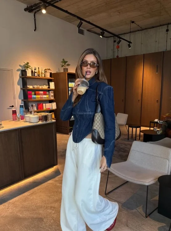 Woman wearing a blue denim button-up shirt with cream wide-leg trousers.