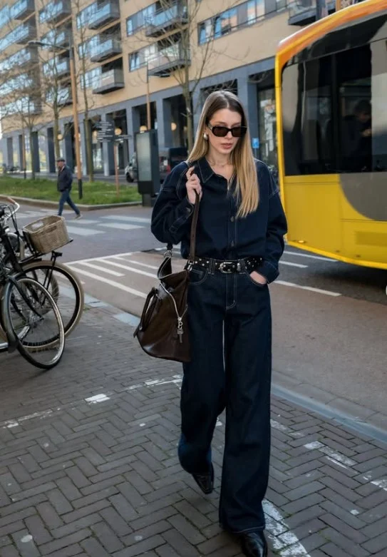 Woman wearing a medium-blue denim button-up shirt with dark straight-leg jeans.