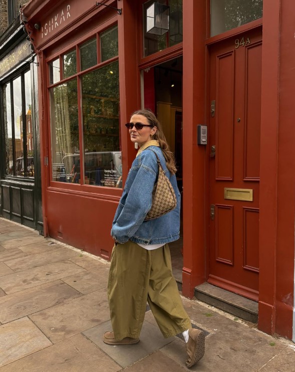 Woman wearing a blue denim button-up shirt with olive utility trousers and loafers.
