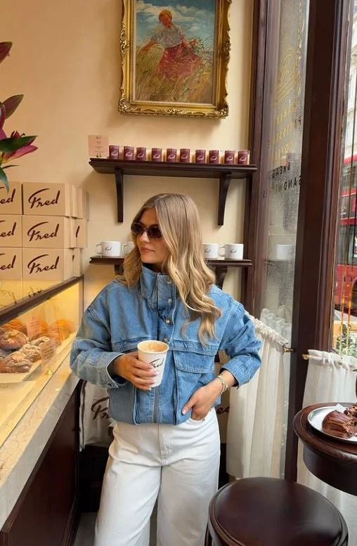 Woman wearing a light-blue denim button-up shirt with white straight-leg jeans.