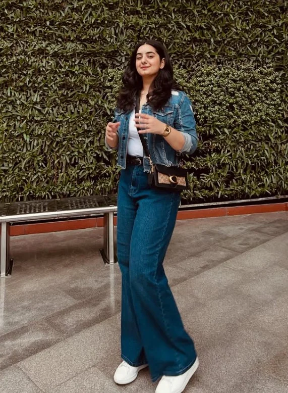 Woman wearing dark blue jeans with a coordinating denim jacket, white T-shirt, and suede loafers.
