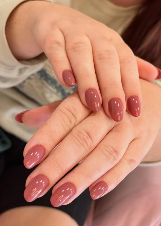 Dusty rose nail varnish on pale skin for a soft muted manicure with an elegant glossy finish.