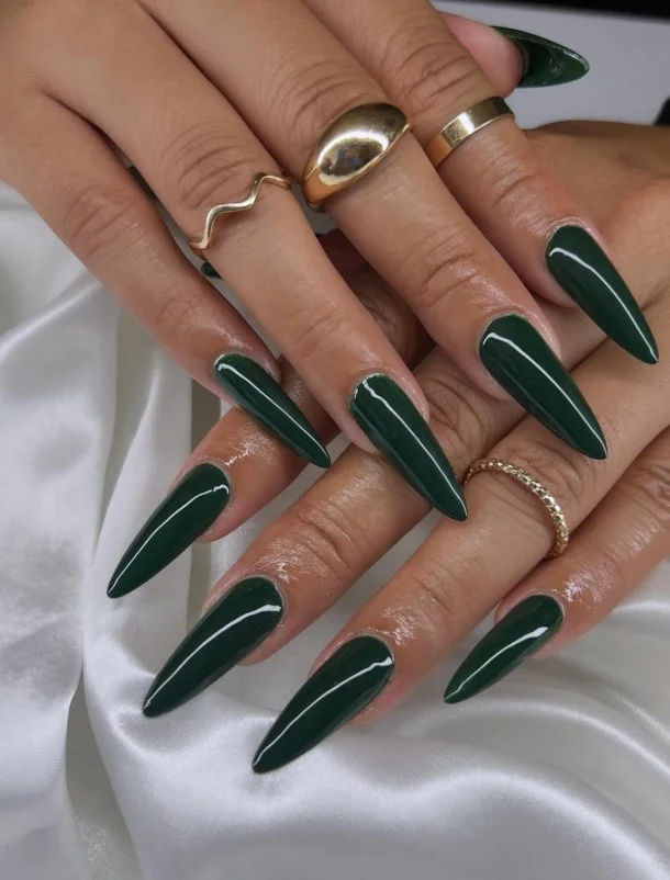 Emerald green manicure creating a luxurious jewel-tone contrast with tan skin.