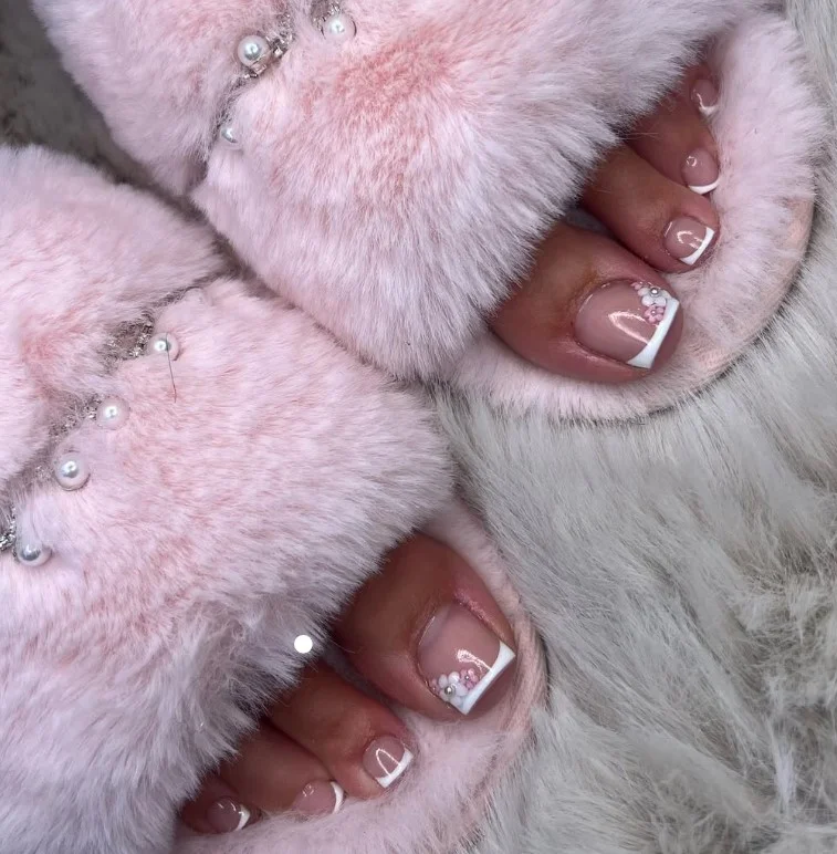 Floral French tip toe nails with delicate flowers along classic white French tips.