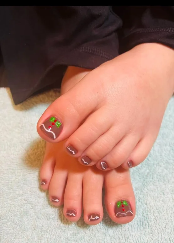 Gingerbread toe nails featuring tiny brown gingerbread figures with white icing details