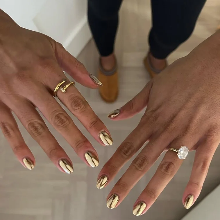 Gold chrome nails creating a reflective luxury manicure on warm tan skin.