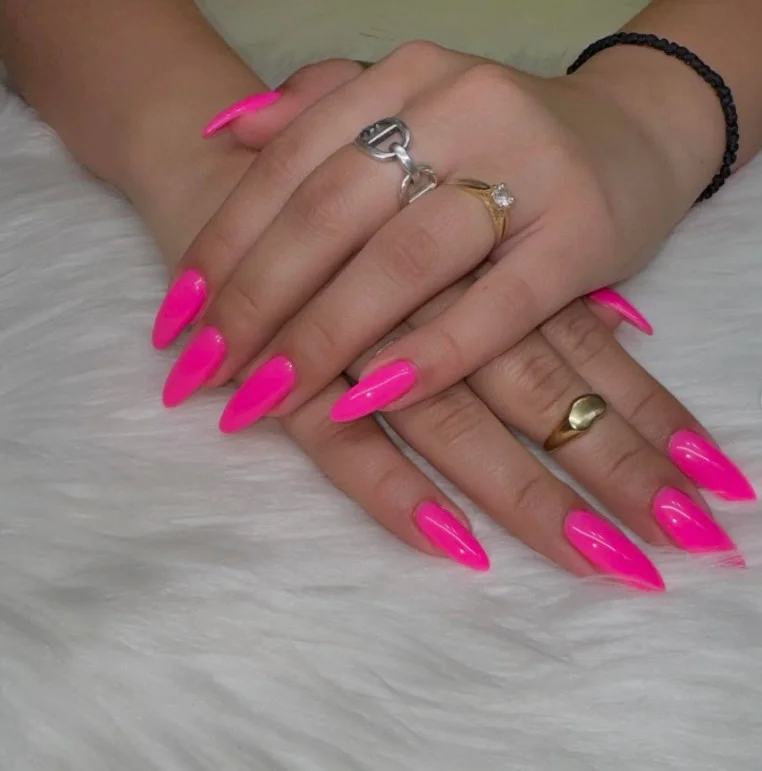Hot pink manicure creating a bright and playful contrast with tan skin.