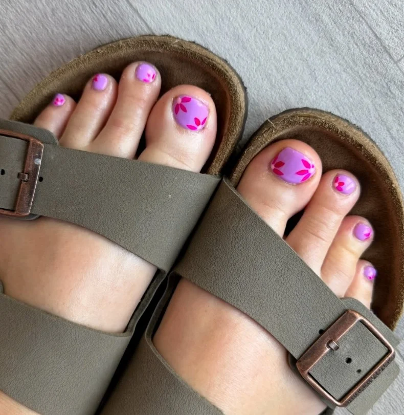 Lavender flower toe nail design with soft purple petals and delicate green stems.