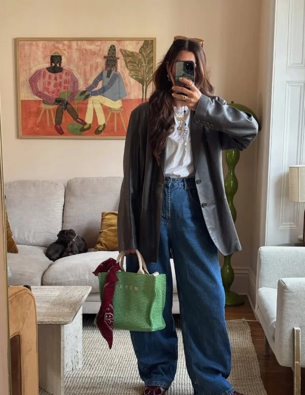 Woman wearing dark blue jeans with a black leather blazer, fitted top, and pointed ankle boots.