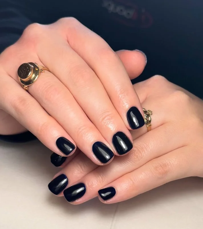 Glossy midnight navy nail varnish creating striking contrast against pale skin.