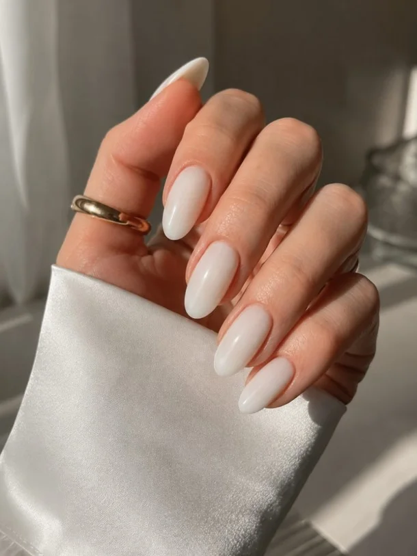 Milky white nail varnish on pale skin creating a soft bright contrast with a clean glossy finish.