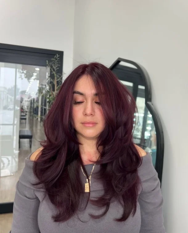 Muted burgundy hair with deep wine tones styled for an elegant evening appearance.