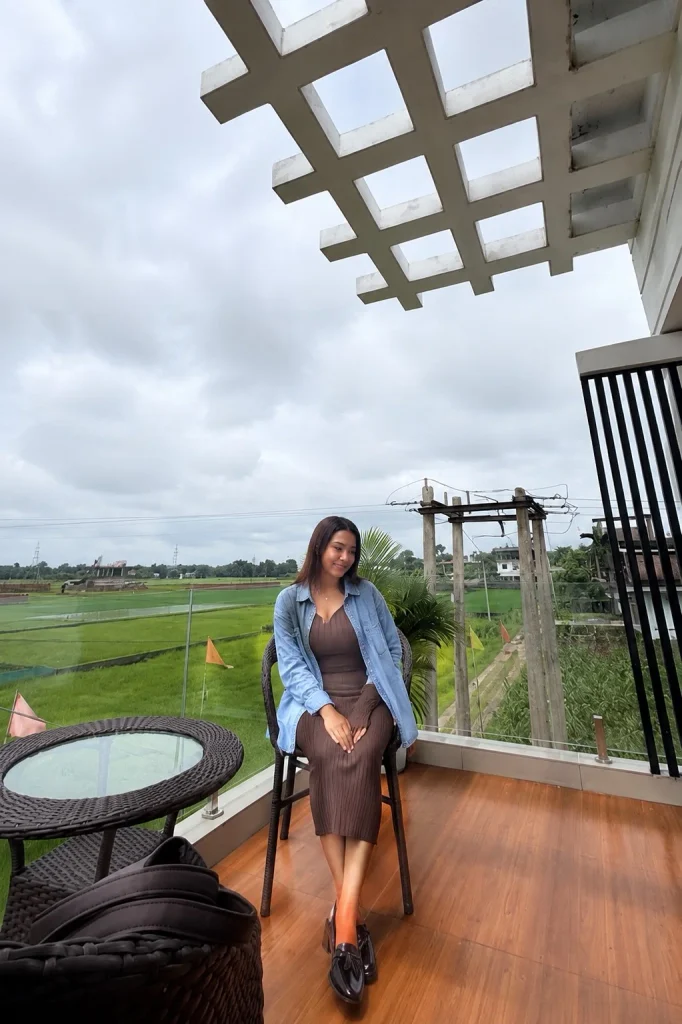 Woman wearing an oversized blue denim button-up shirt over a ribbed column dress.