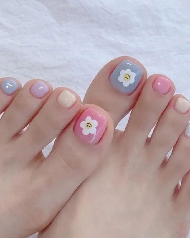 Pastel flower toe nail design featuring soft pink, lavender, blue, and yellow floral details.