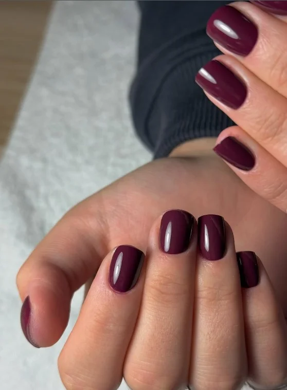 Deep plum nails creating an elegant contrast against a tan complexion.