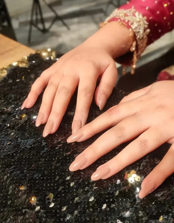 Sandy beige nail varnish complementing pale skin with a polished neutral manicure style.