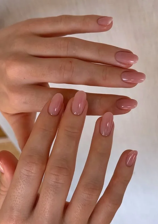 Sheer pink nail varnish on pale skin with a glossy natural finish for an elegant everyday manicure.