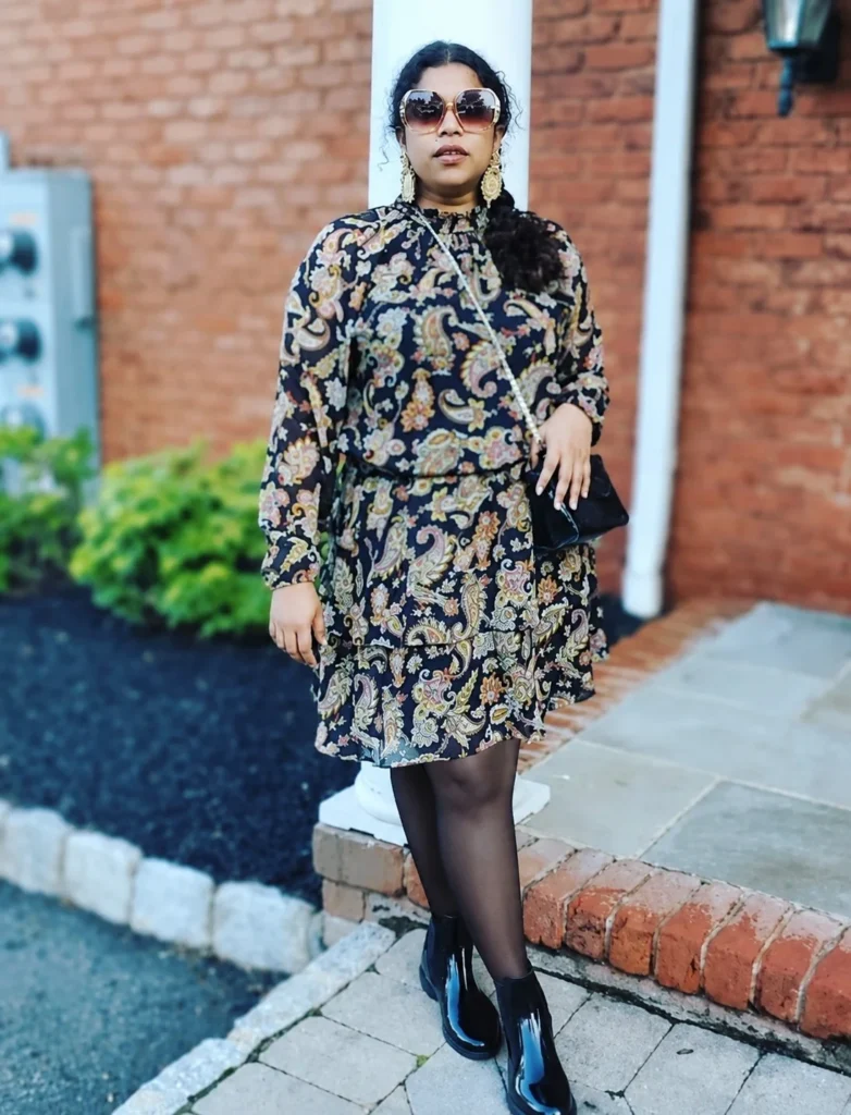 Woman wearing short rain boots with a mini skirt, opaque tights, chunky sweater, and long coat.