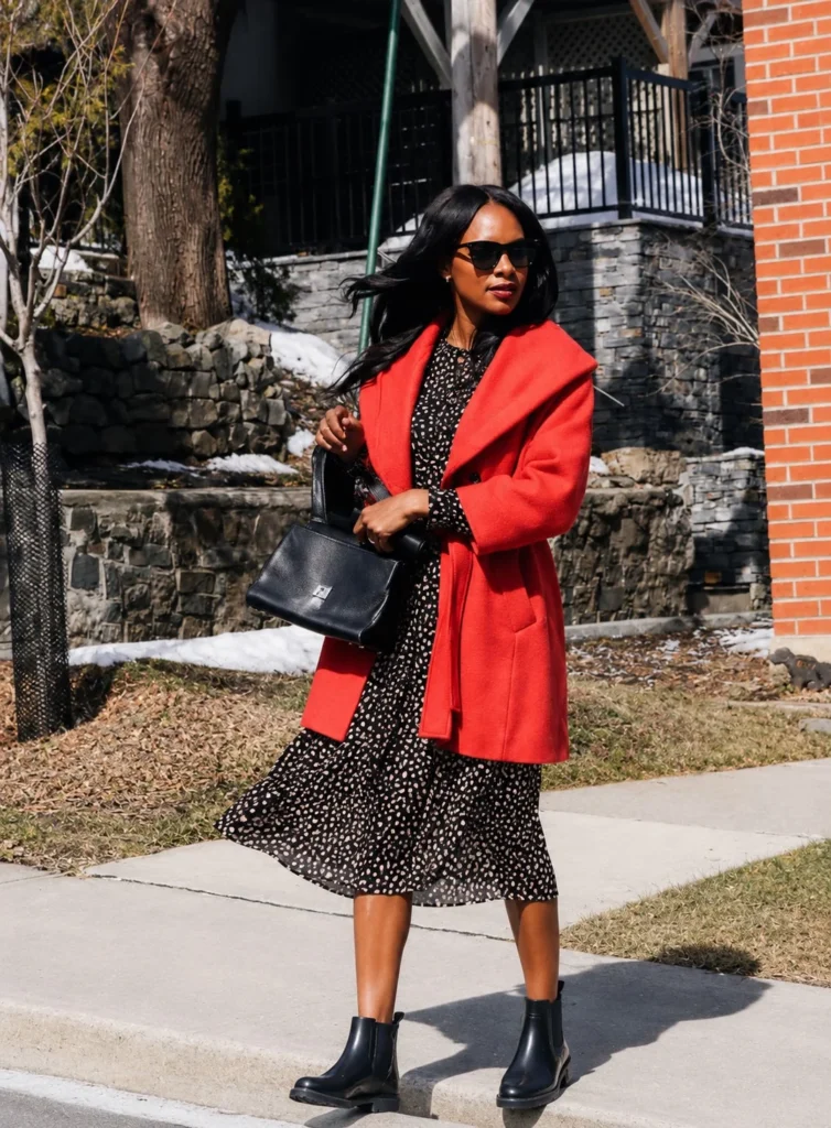Woman wearing short rain boots with a printed midi dress and a trench coat.