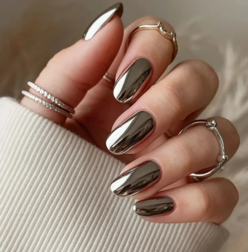Silver chrome nail varnish creating a reflective modern manicure against pale skin.