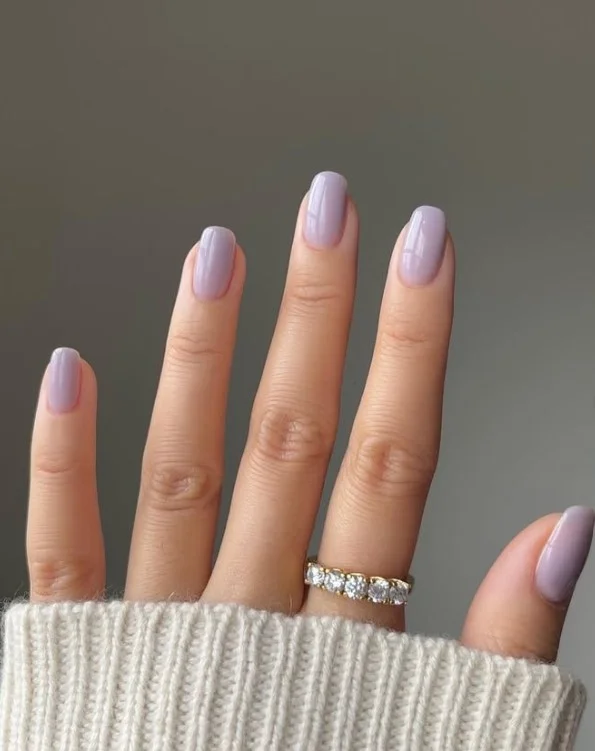 Soft lavender nail varnish on pale skin for a delicate cool-toned pastel manicure.