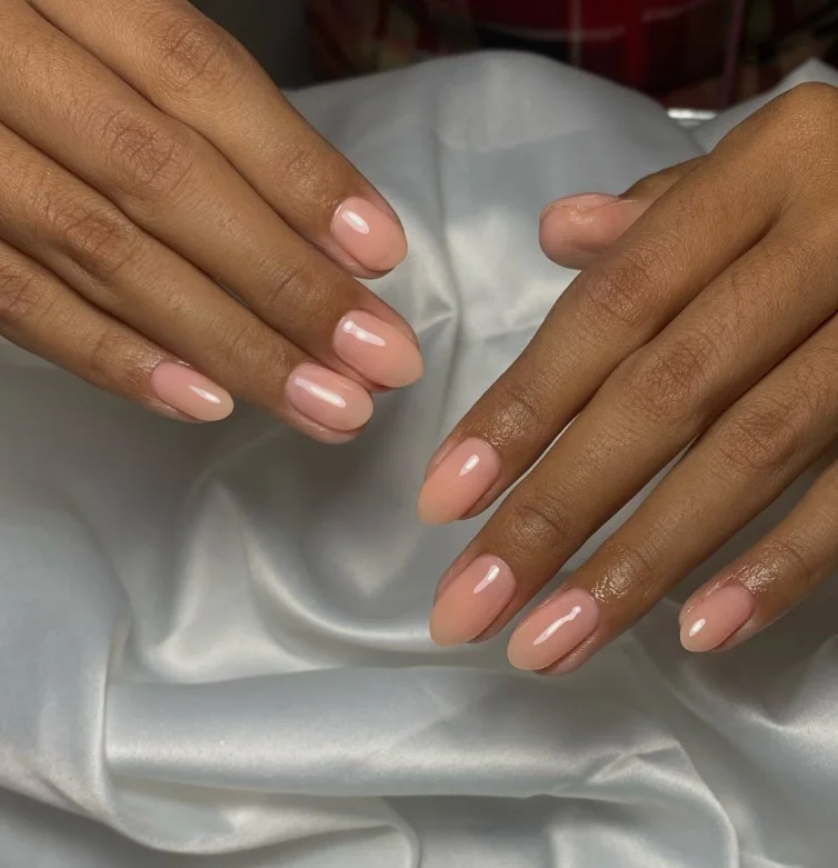 Soft peach nail polish adding a warm and feminine glow to tan skin.