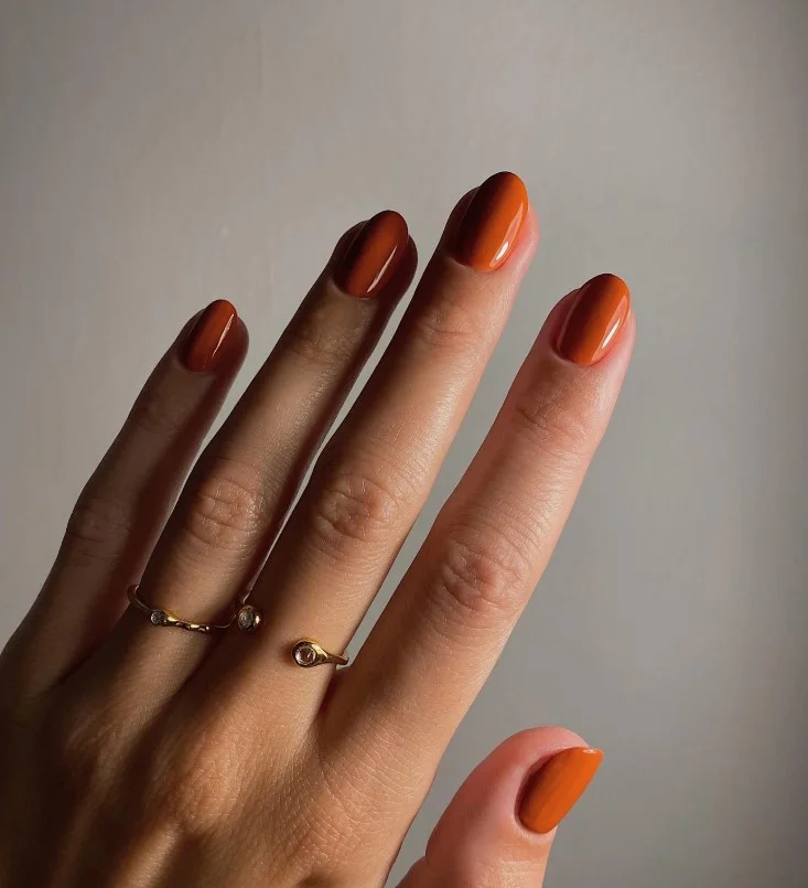 Terracotta nail polish enhancing warm tan undertones with an earthy finish.