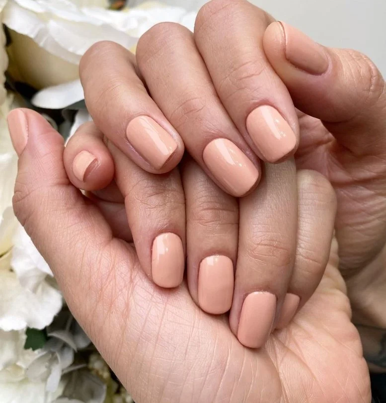 Warm nude nail polish on tan skin creating a polished and natural manicure.