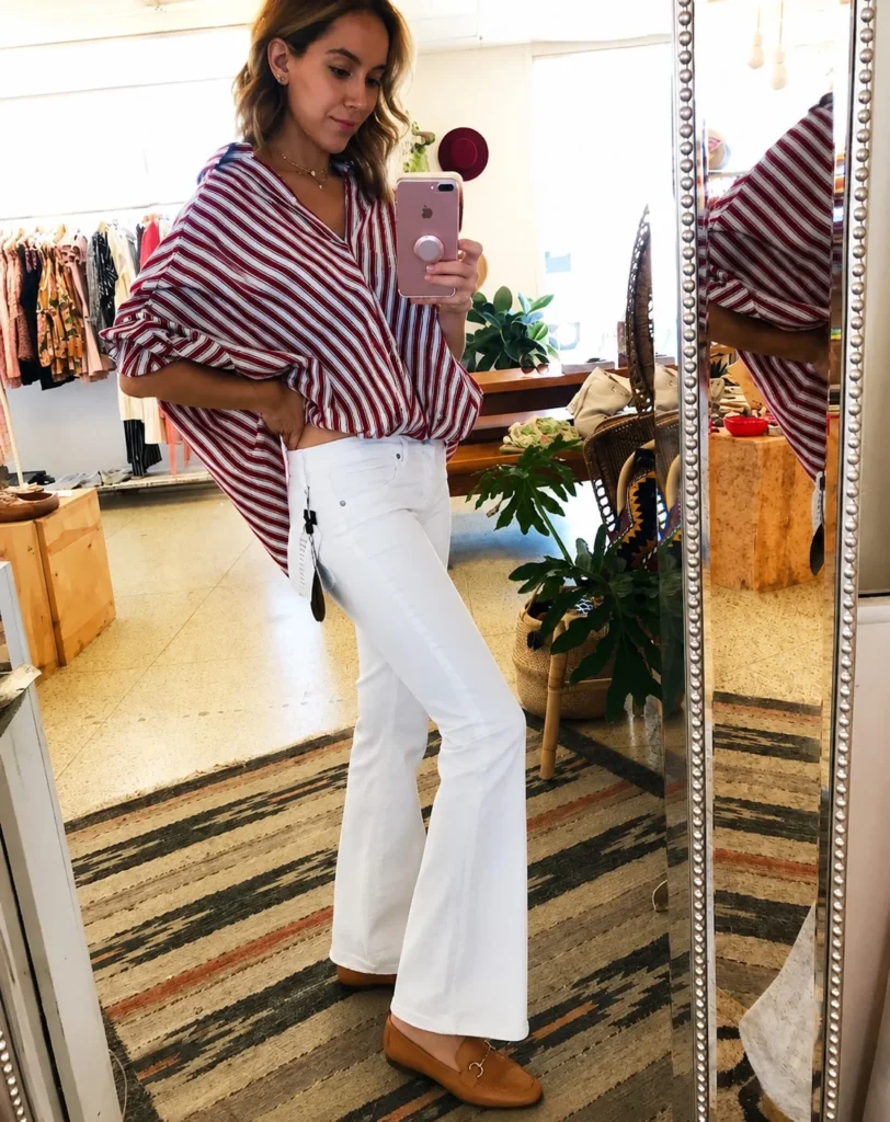 Woman wearing straight-leg white jeans with a tucked blouse, leather belt, and loafers for a polished casual outfit.