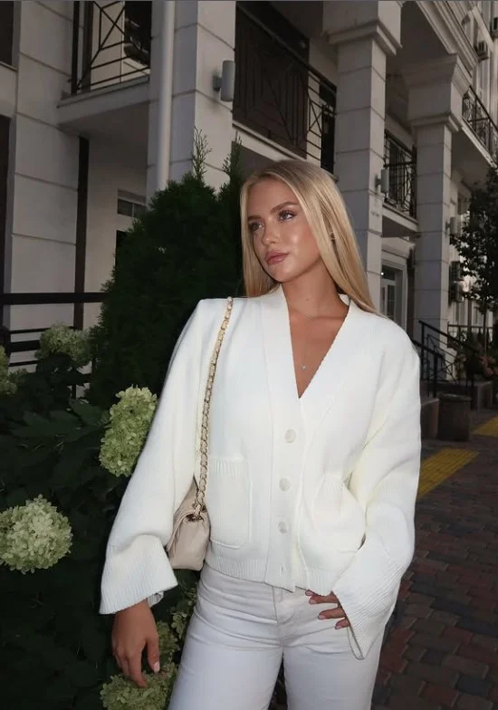 Woman wearing high-rise white jeans with a cropped cardigan and ballet flats for a feminine polished outfit.