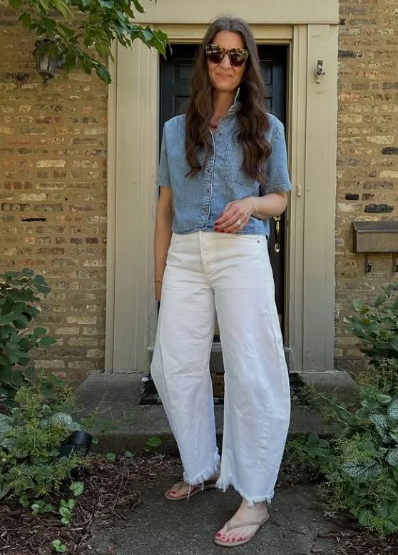 Woman wearing white jeans with a blue denim shirt, brown belt, and casual leather accessories for a relaxed denim outfit.